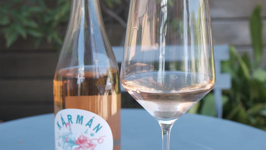 A glass of Spanish rose wine Karman sitting on a table next to the open bottle