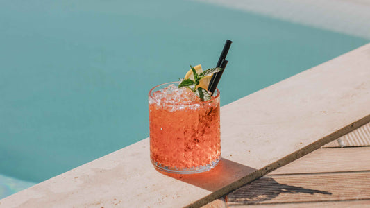 A cocktail sitting on the edge of a swimming pool